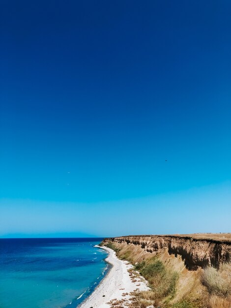 Klippe Meer blaue Aquamarinwellen säumen sonnigen Strand. weiche Welle von Ozeanschaum. natürlicher Hintergrund Himmel