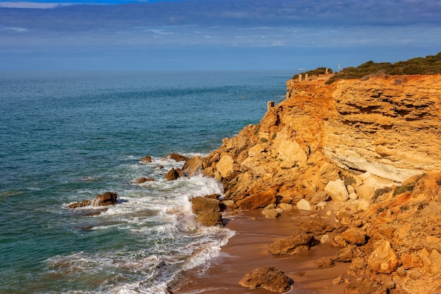 Klippen mit gefährlichem Treppenhaus zum Strand im Hintergrund