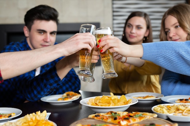 Klirrendes Bier in der Nähe von Pizza in der Bar