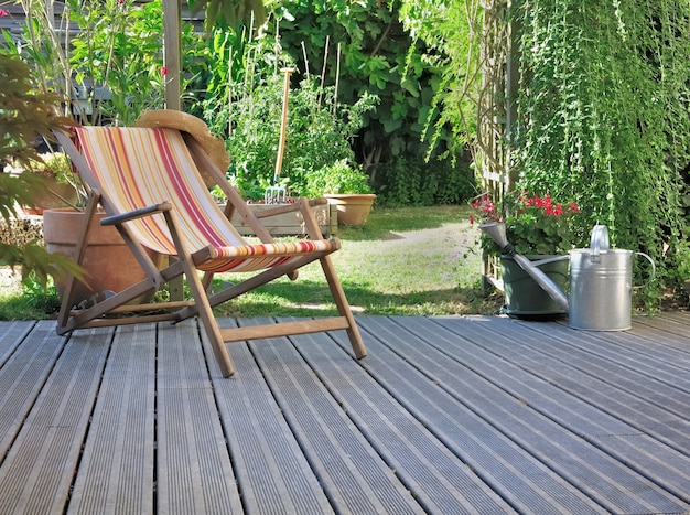 Klubsessel auf Holzterrasse in einem Hausgarten