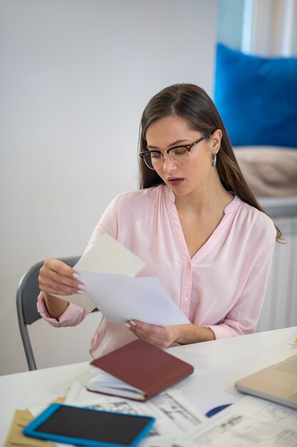 Kluge attraktive Frau, die die Entwürfe betrachtet, während sie sich auf ihre Arbeit konzentriert