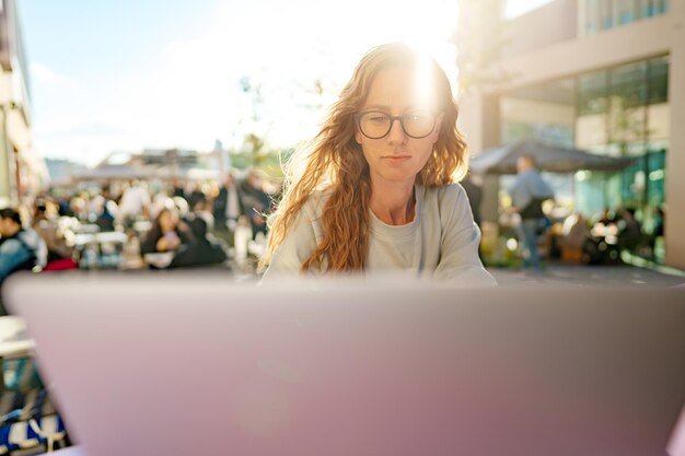 Kluge Frau mit Brille sitzt im Café mit Laptop