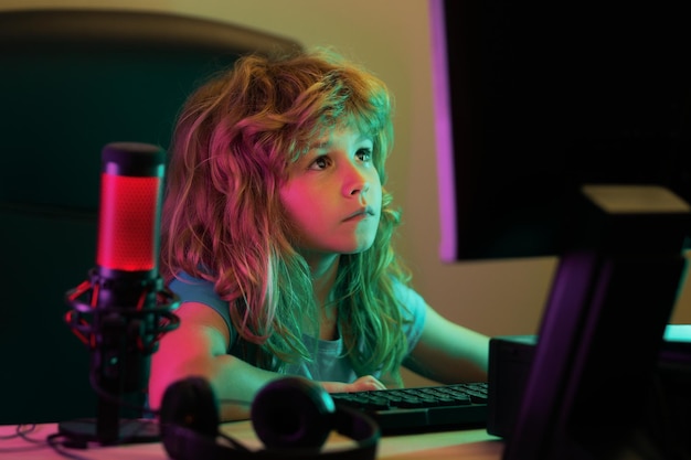 Kluge Kinder, die online lernen, zu Hause, kaukasischer Kinderjunge, der nachts in einem dunklen Raum am Laptop arbeitet, ein hübsches