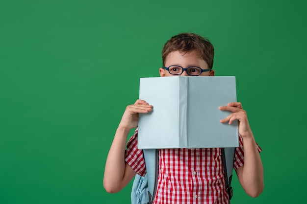 Kluger Junge mit Brille versteckt sein Gesicht hinter einem Buch