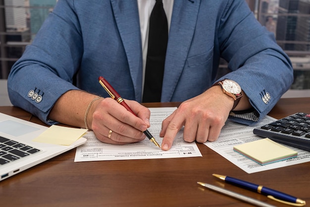 Kluger männlicher Geschäftsmann, der mit wichtigen Dokumenten am Schreibtisch arbeitet