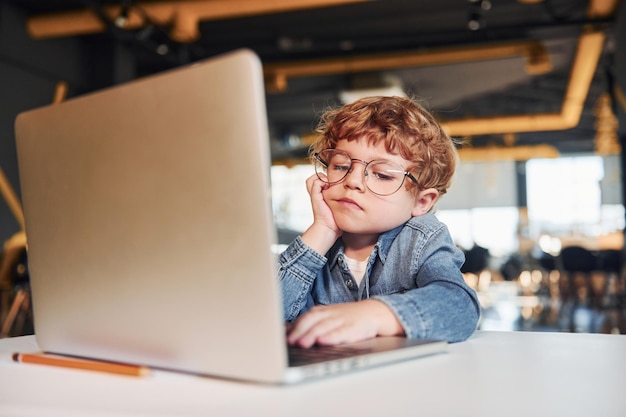 Kluges Kind in Freizeitkleidung und Brille mit Laptop für Bildungszwecke