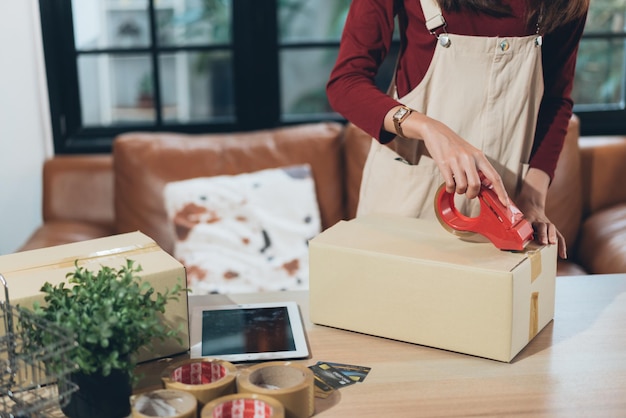 KMU-Kleinunternehmerin verpackt und klebt Kartonunternehmerin oder Ladenbesitzerin, die zu Hause arbeitet