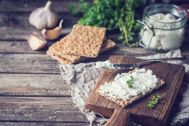 Knäckebrottoast mit hausgemachtem Kräuter-Knoblauch-Hüttenkäse auf Holzuntergrund