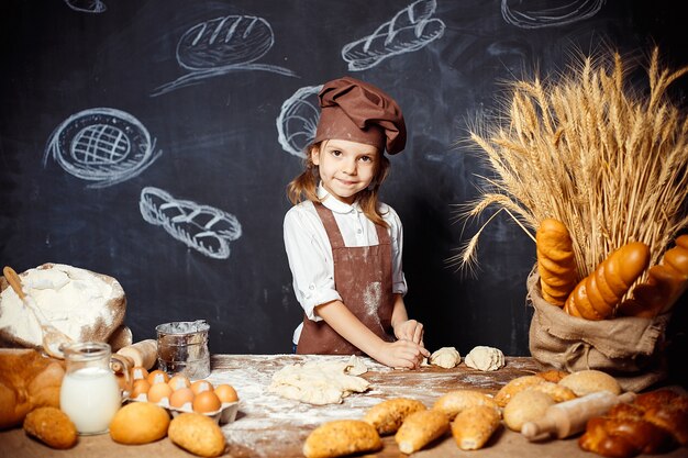 Knetender Teig des kleinen Mädchens bei Tisch