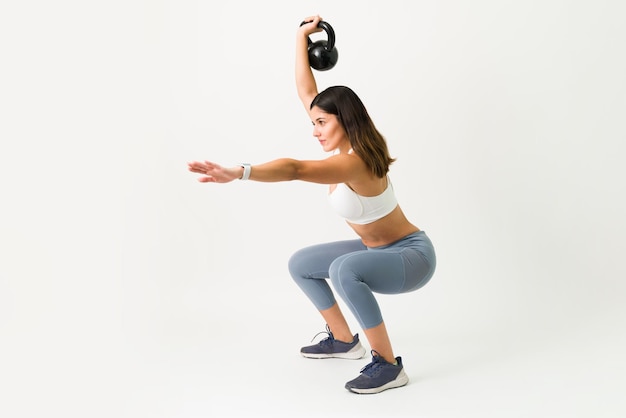 Kniebeugenübungen mit einer Kettlebell. Starke kaukasische Frau, die hockt, während sie ein Kettlebell-Gewicht hält, um ihre Arme, Beine und ihren Rücken zu trainieren