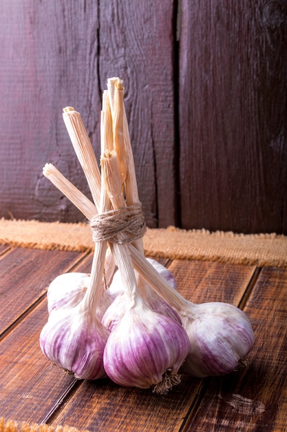 Knoblauch gewickelt mit Schnur auf hölzernem Hintergrund. Rustikal.