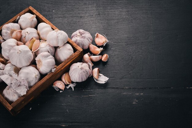 Knoblauch in einem Holzkorb Frischer Knoblauch auf einem hölzernen Hintergrund Ansicht von oben Freier Platz für Text