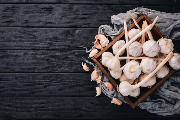 Knoblauch in einem Holzkorb Frischer Knoblauch auf einem hölzernen Hintergrund Ansicht von oben Freier Platz für Text