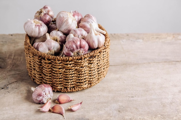 Knoblauch in einem Weidenkorb auf einem Holztischhintergrund