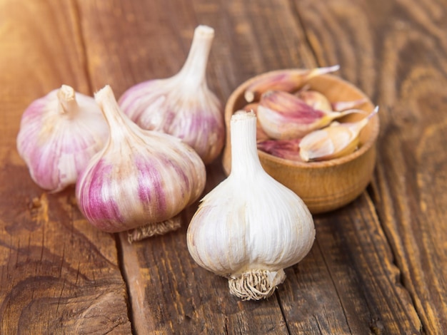 Knoblauch Knoblauchzehe Flasche Knoblauch in einer Holzschale auf HolzhintergrundGesundes Ernährungskonzept