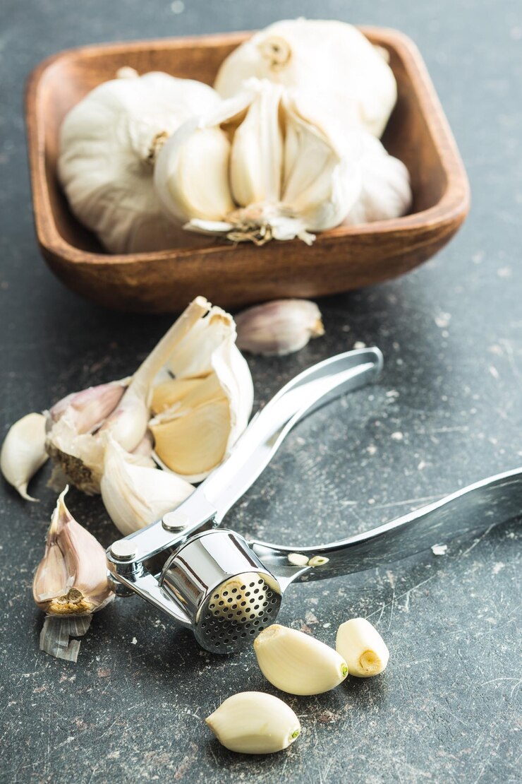Foto knoblauch und knoblauchpresse auf küchentisch