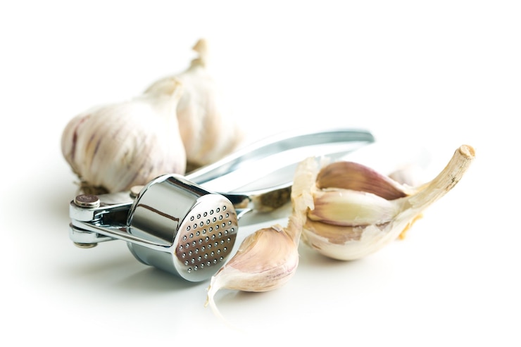 Foto knoblauch und knoblauchpresse isoliert auf weißem hintergrund