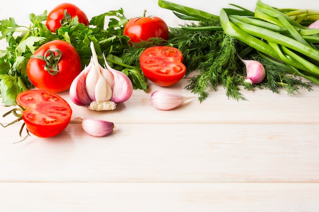 Knoblauch und Tomate auf dem weißen hölzernen