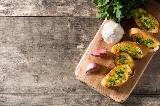 Knoblauchbrotscheibe und Zutaten auf Holztisch, Draufsicht