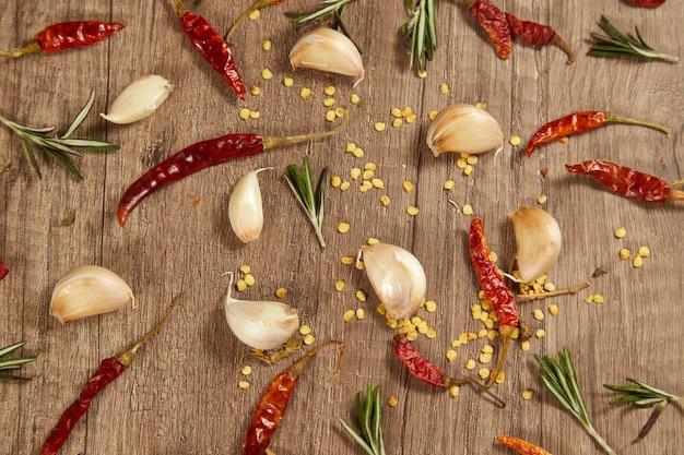 Knoblauchzehen mit Rosmarin und Chili auf einem Tisch.