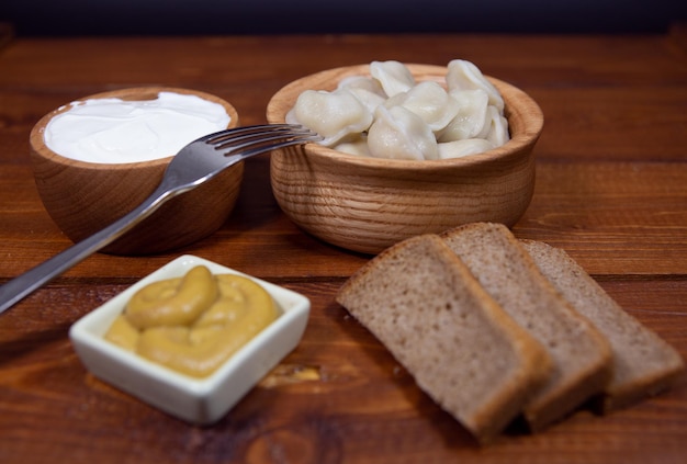 Knödel auf einem Holztisch mit Senf und Sauerrahm sowie Roggenbrotravioli Nahaufnahmefoto