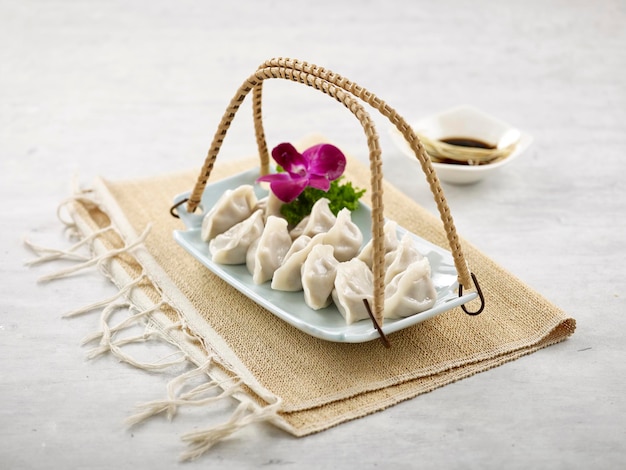 Knödel gefüllt Gedämpfter Gyoza in einer Schüssel mit Dip-Sauce auf Serviettenseitenansicht auf grauem Hintergrund