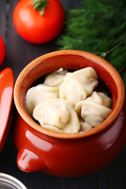 Knödel in einem Topf Closeup Gemüse und Sauerrahm. Russische Pelmeni, Teigtaschen mit Fleisch