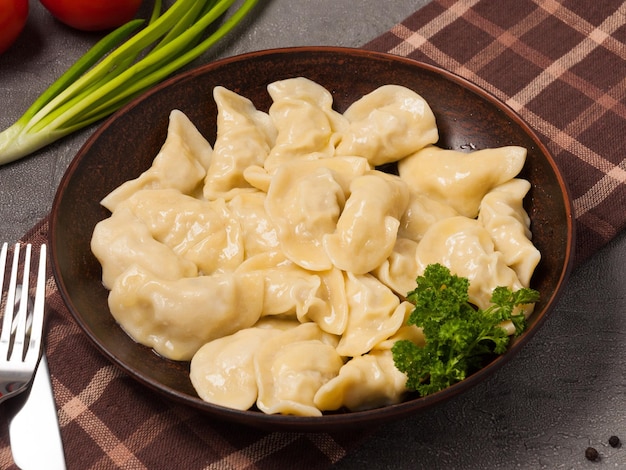 Knödel mit Hühnerfleisch auf einem mit Kräutern dekorierten Tonteller