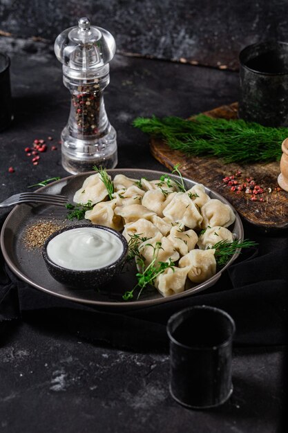 Knödel mit Sauerrahm und Kräutern auf einem dunklen Teller Fleischknödel