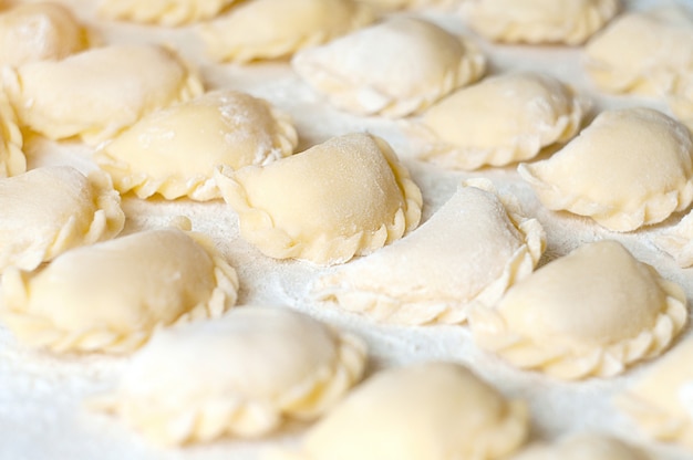 Knödel (Vareniki) mit Kartoffeln - traditionelles ukrainisches Essen. Rohe Knödel mit Kartoffeln kochen