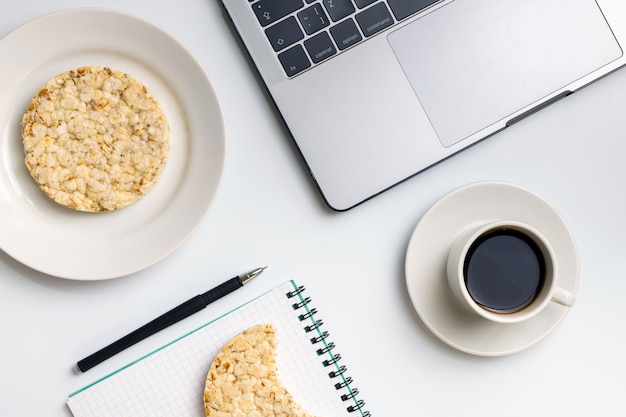 Knusperige Reisrunden mit Kaffee in der Nähe von Laptop und Notebook.