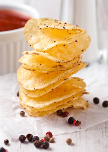 Knusperiger köstlicher Pfefferkartoffelchips-Chipsnack auf weißem hölzernem Brett mit Soße und Salz