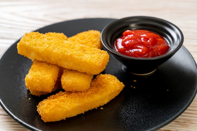 knusprig gebratene Fischstäbchen mit Semmelbröseln auf Teller mit Ketchup serviert