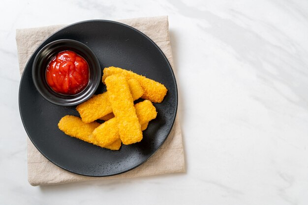 knusprig gebratene Fischstäbchen mit Semmelbröseln auf Teller mit Ketchup serviert