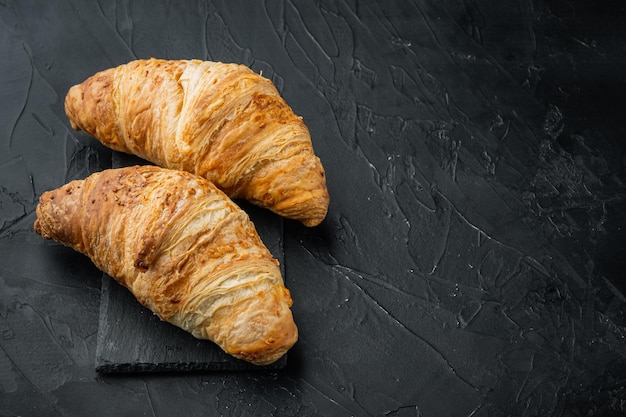 Knusprige frische Croissants auf schwarzem Steinhintergrund mit Kopienraum für Text