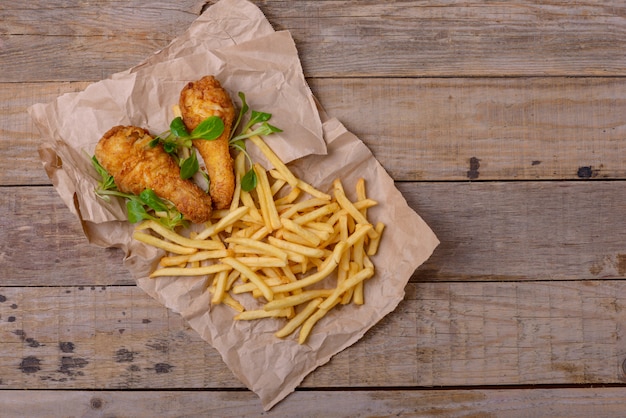 Knusprige gebratene Hähnchenschenkel und viel Grün mit Pommes Frites