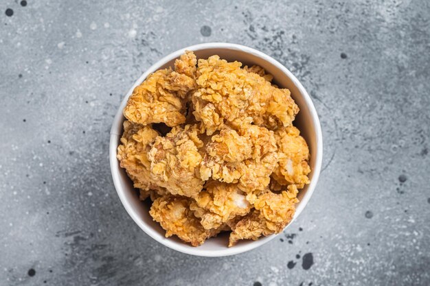 Knusprige Hühnchen-Popcorn-Häppchen in einem Korb aus Fastfood Grauer Hintergrund Ansicht von oben