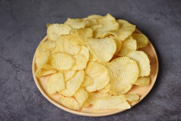 Knusprige Kartoffelchips auf dem schwarzen Hintergrund des Küchentisches Kartoffelchips Snack auf Platte Draufsicht