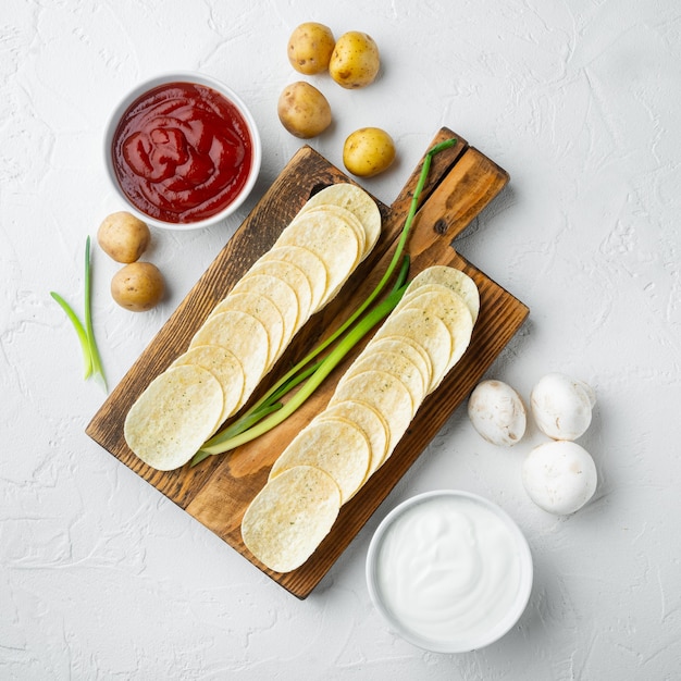 Knusprige Kartoffelchips mit Dip-Saucen-Tomatendip-Sauerrahm auf weißer Steinoberfläche