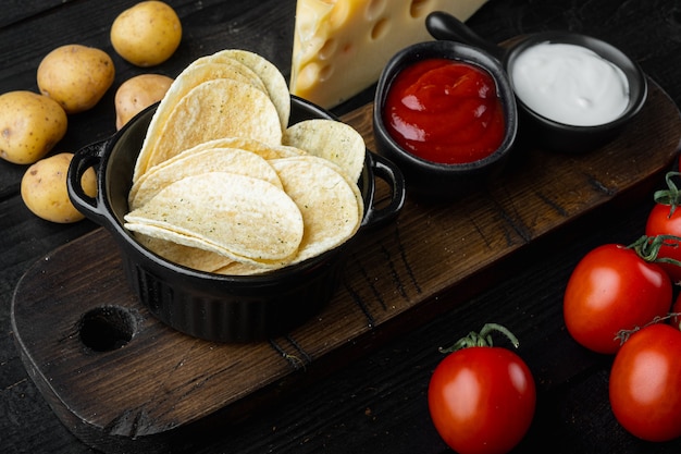 Knusprige Kartoffelchips mit Käse und Zwiebeln auf schwarzem Holz