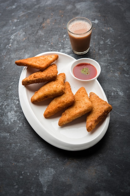 Knusprige Kartoffeldreiecke oder Batata Vada mit Semmelbrösel bedeckt und dann frittiert. serviert mit Tomatenketchup. selektiver Fokus