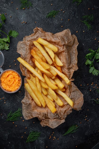 Knusprige leckere Pommes Frites auf dunklem Steinhintergrund mit Käsesauce. Fastfood-Restaurant. Gesunde Alternative zu Fast Food. Bratkartoffeln