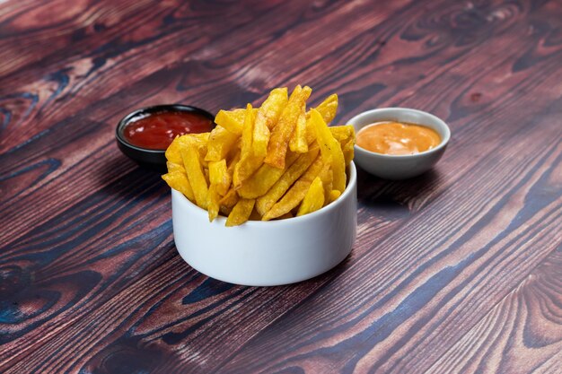 Knusprige Pommes Frites oder Kartoffelchips mit Mayo-Dip und Tomatensoße, serviert in einer Seitenansicht des Tellers