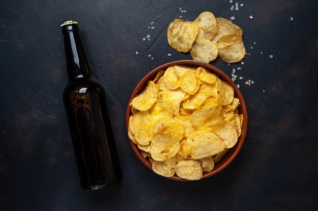 Knusprige Pommes in einer Schüssel und Bier auf einem Steinhintergrund