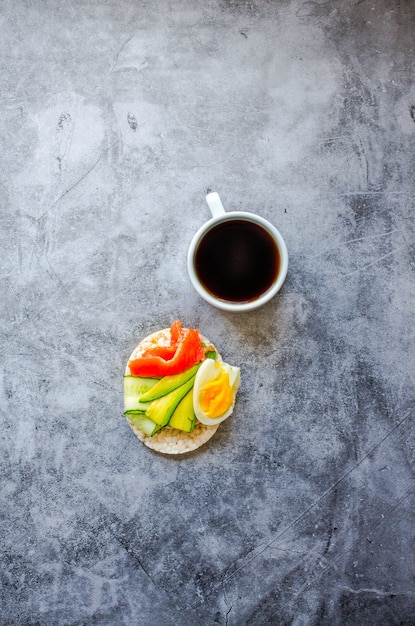 Knusprige Reiskuchen mit Avocado und frischem gesalzenem Lachsfilet mit Eiern auf grauem Marmorhintergrund. Ansicht von oben. Platz für Text. Proteinreiche und kohlenhydratarme Mahlzeit.