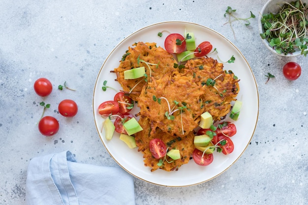 Knusprige Süßkartoffel-Krapfen, serviert mit Tomaten, Avocado und Microgreens