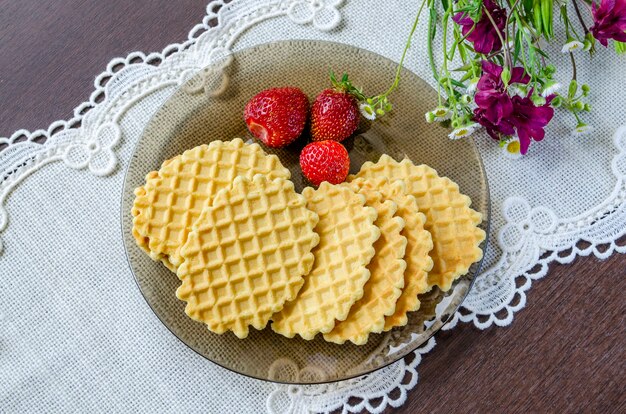 Knusprige Waffeln mit Erdbeeren auf einem dunklen Teller auf einer weißen Serviette