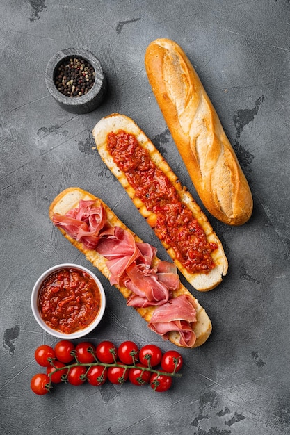 Knuspriger Toast mit frischen Tomaten und Rohschinken auf grauem Steintisch Hintergrund Draufsicht flach gelegt