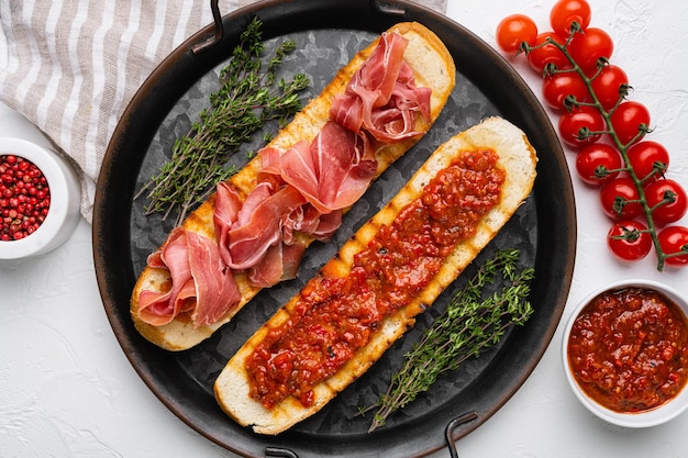 Knuspriger Toast mit frischen Tomaten und Rohschinken auf weißem Steintisch Hintergrund Draufsicht flach gelegt