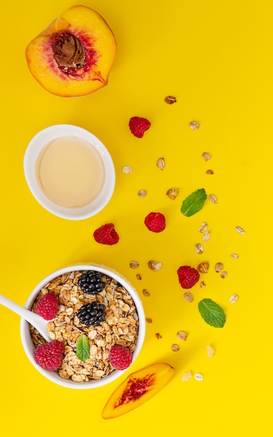 Knuspriges Müsli, Beeren und Minze mit Beeren, Pfirsich und Honig. Gesundes Frühstückskonzept.